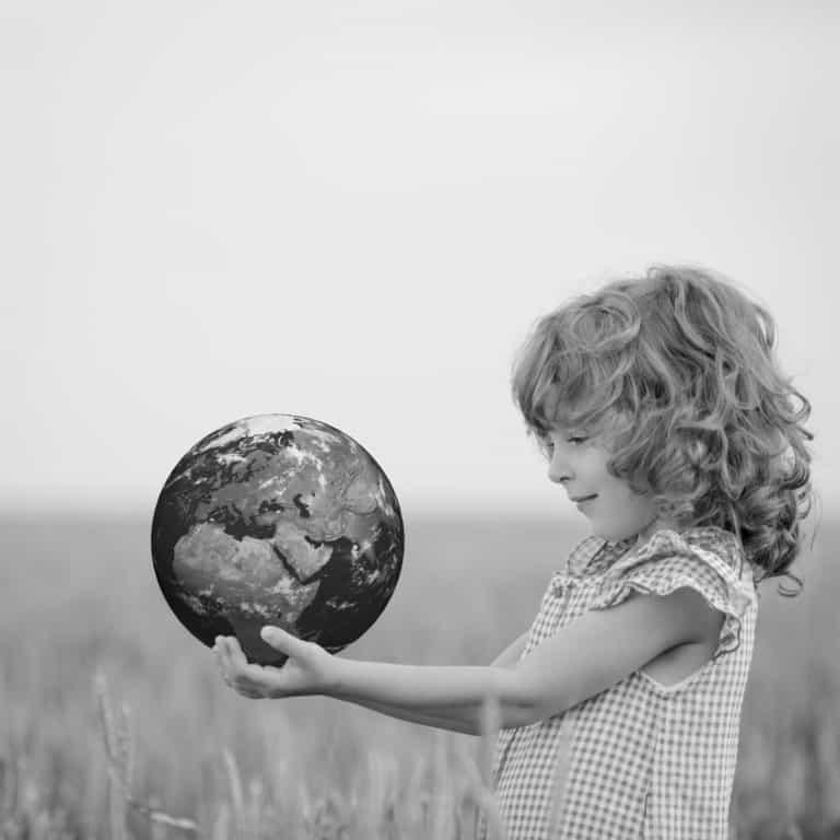 Child holding Earth in hands against green spring background. Elements of this image furnished by NASA